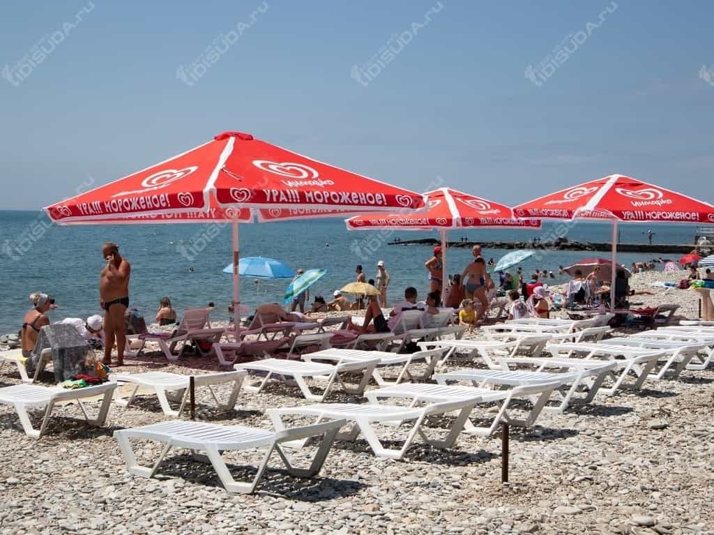 лежаки, зонтики и туристы на галечном пляже санатория Факел в Дивноморcком