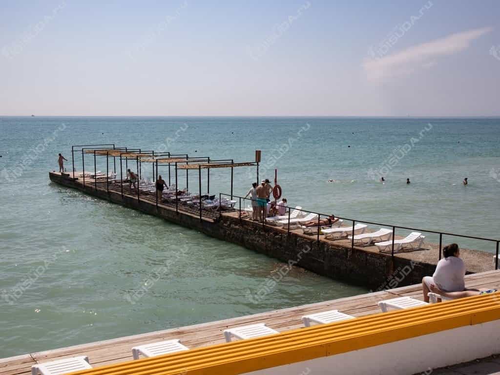 Пляж с бетонным настилом, волнорезом и лежаками в Дивноморском